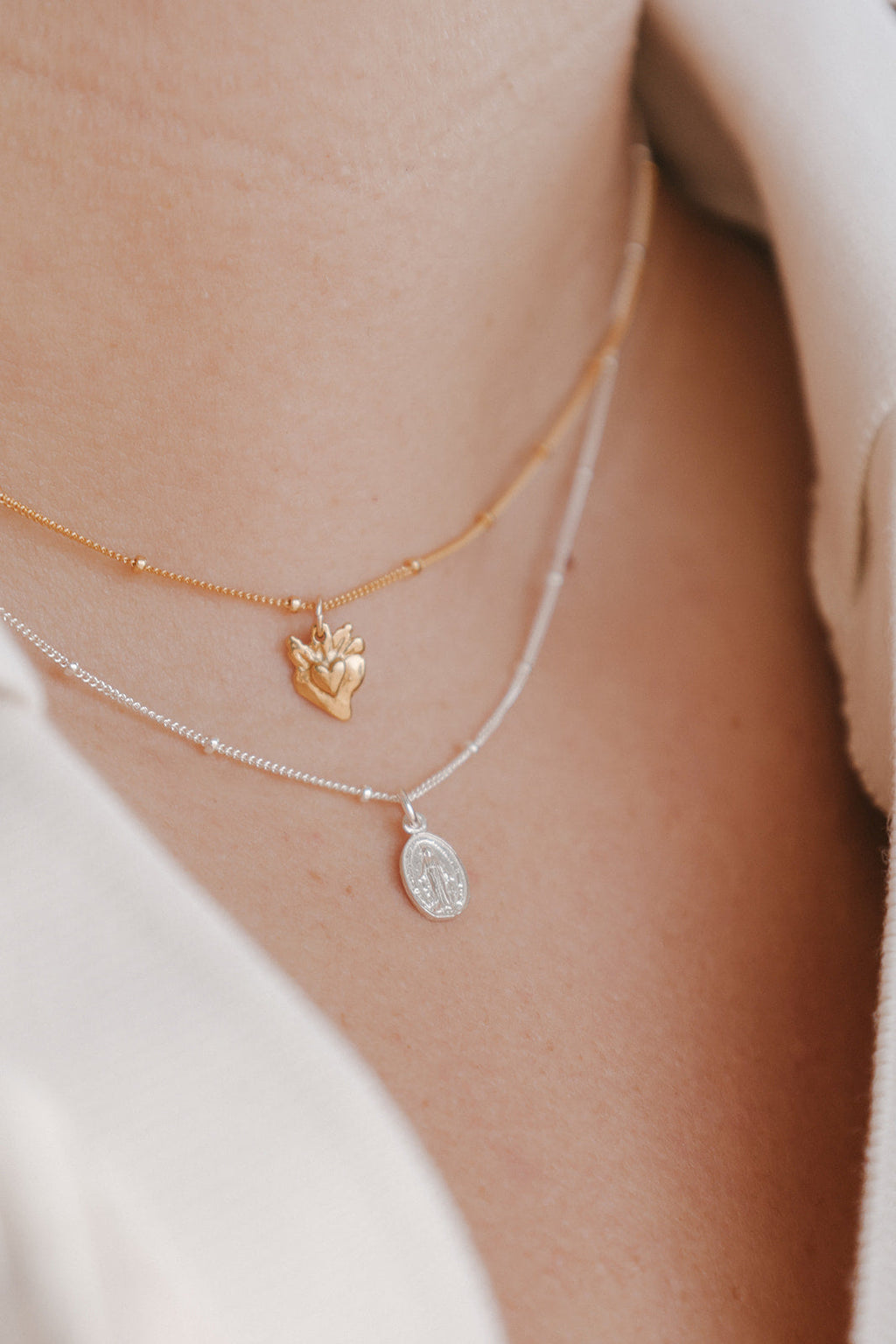 Two-layer necklace with gold-tone and silver-tone chains, oval miraculous medal pendants