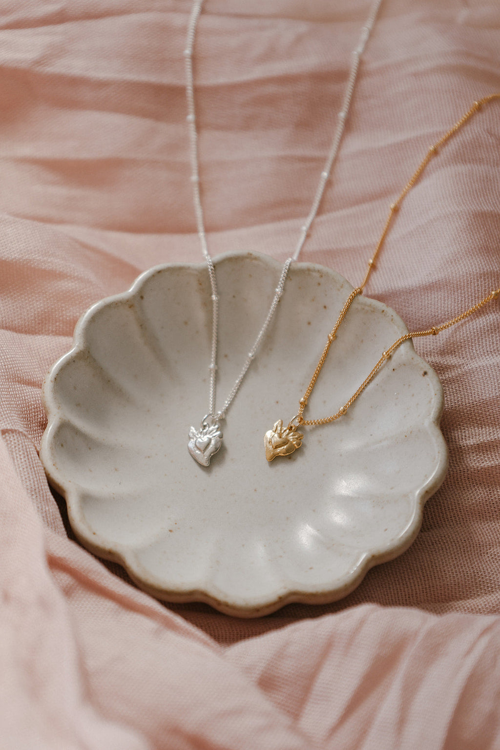 Heart pendant necklaces with gold and silver chains, each with tiny sacred-heart charm
