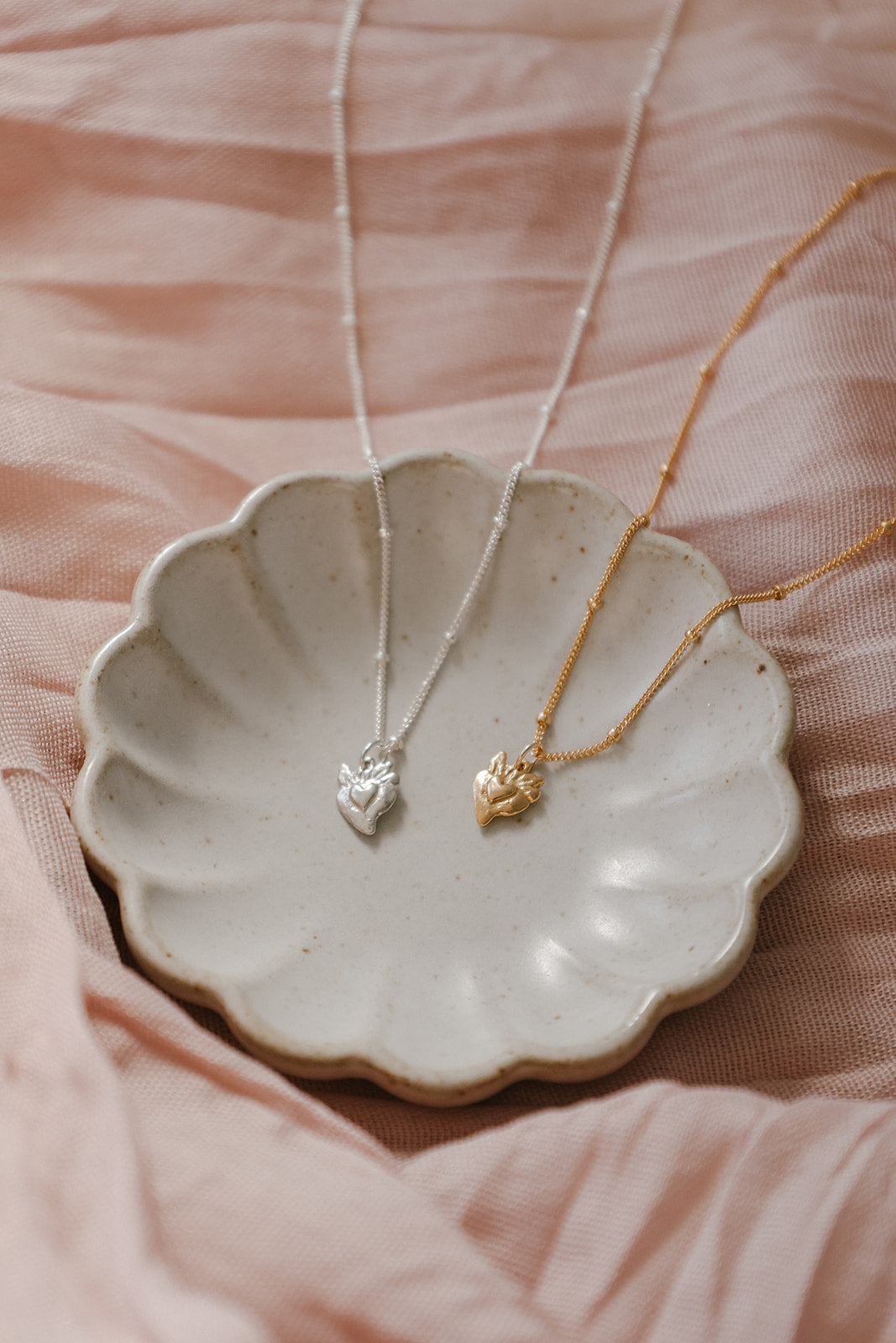 Heart pendant necklaces with gold and silver chains, each with tiny sacred-heart charm
