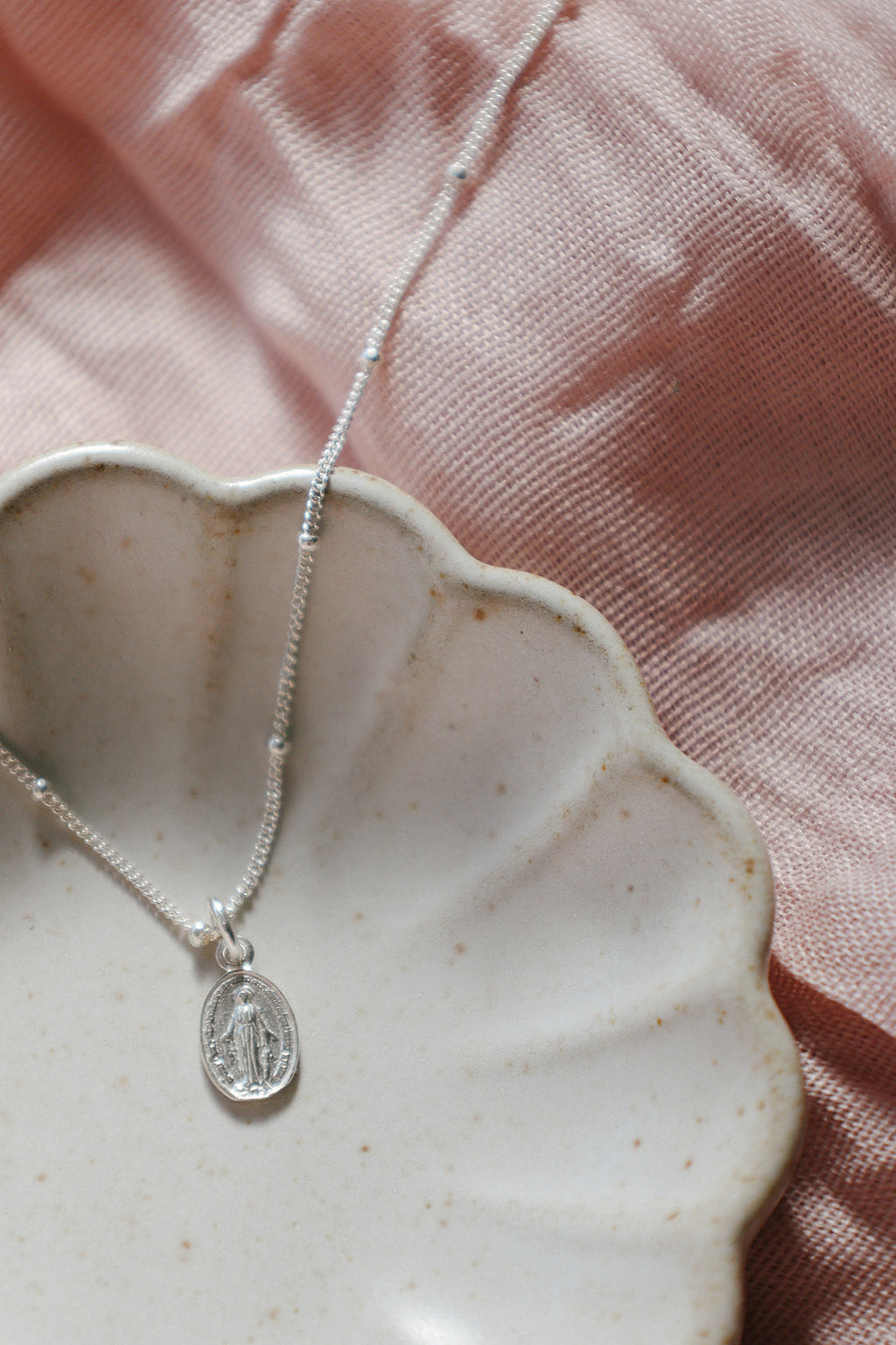 Sterling silver oval medal charm necklace, layered on pleated fabric