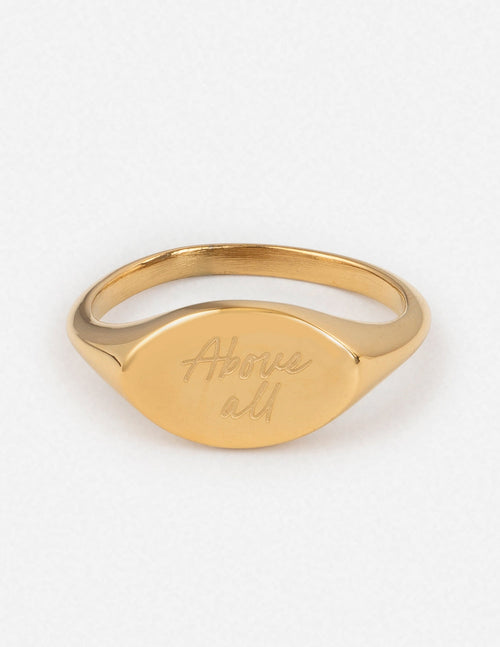 Gold oval signet ring with engraved script on the front