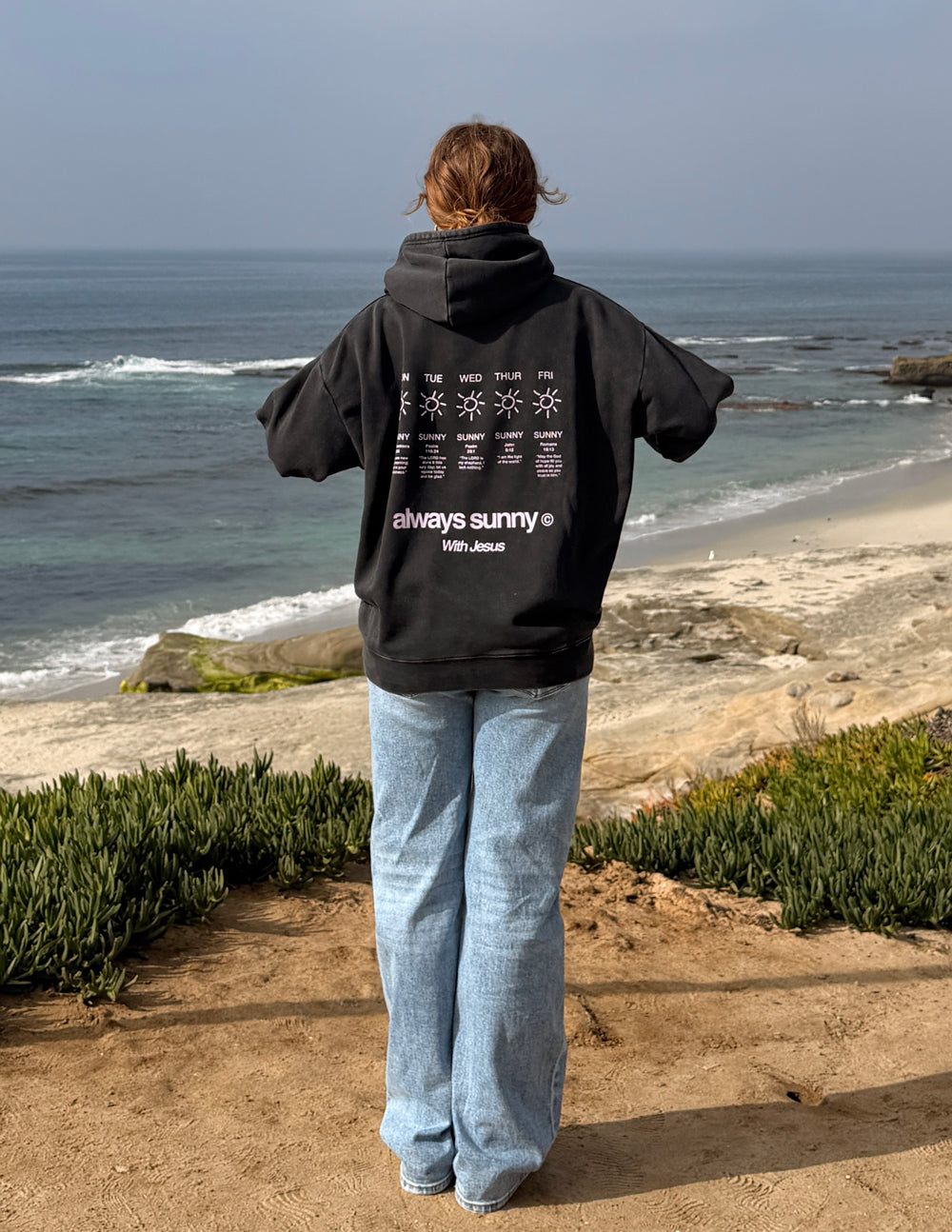 Unisex charcoal hoodie with rear graphic of sun icons and “always sunny”, hooded back view
