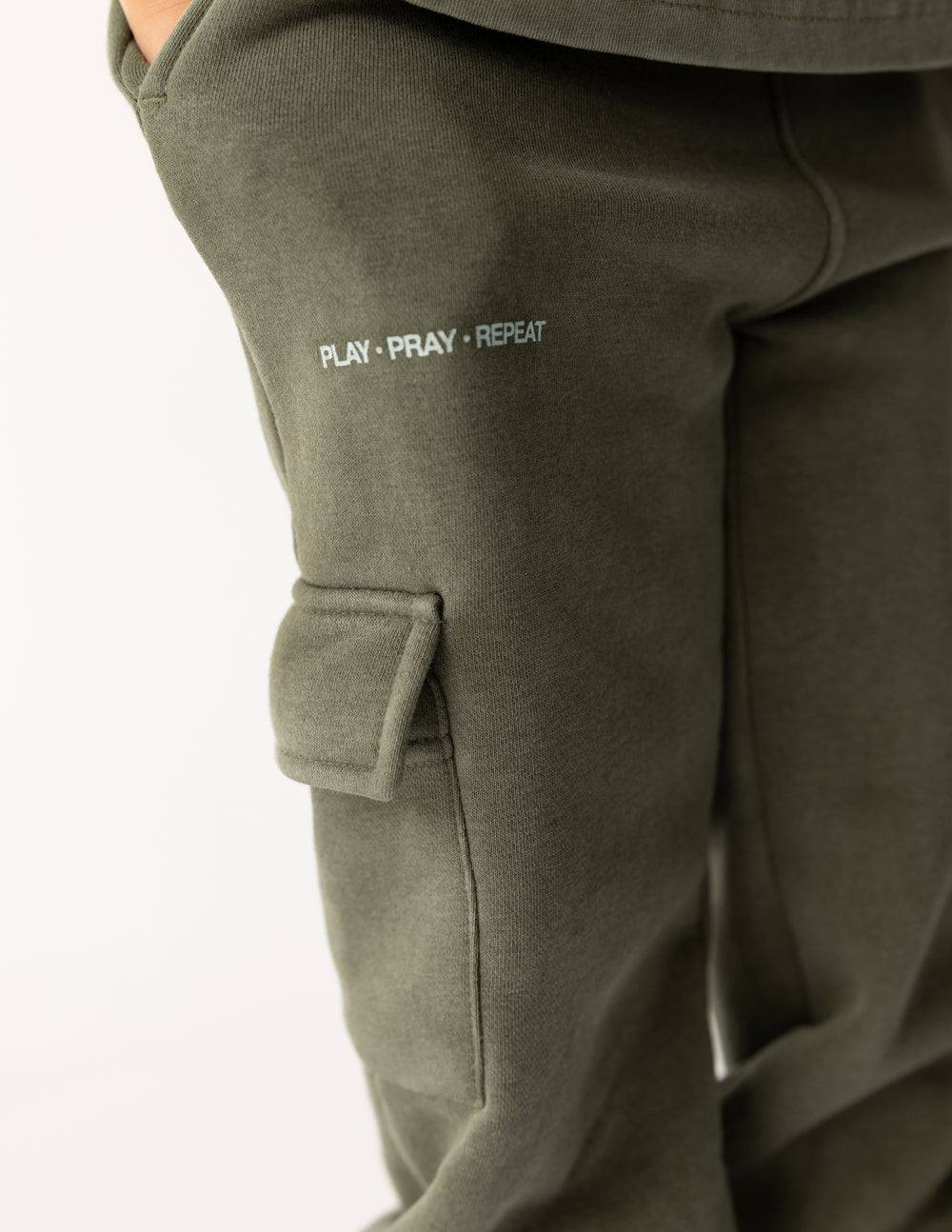 Kids cargo sweatpants with PLAY–PRAY–REPEAT text near pocket and flap detail