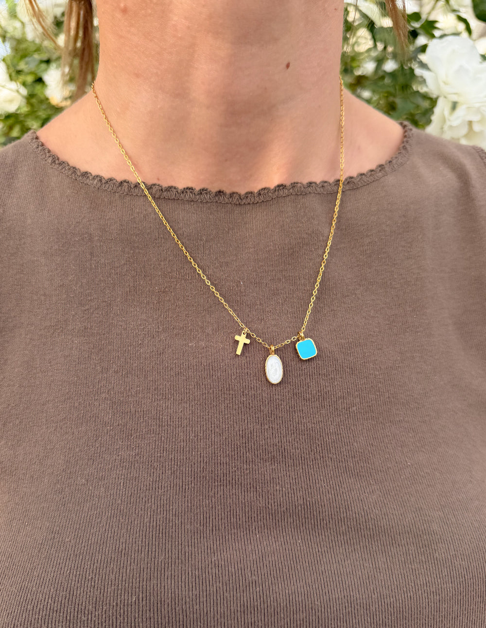 Gold charm link necklace with cross, white oval, and blue square charms
