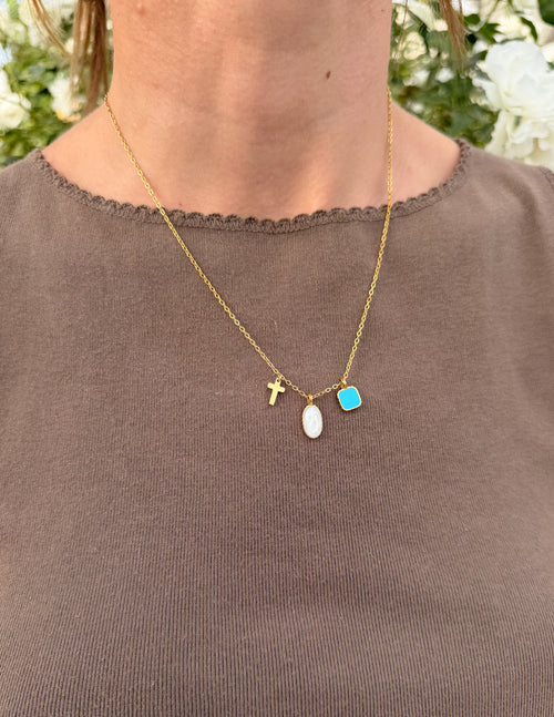 Gold charm link necklace with cross, white oval, and blue square charms