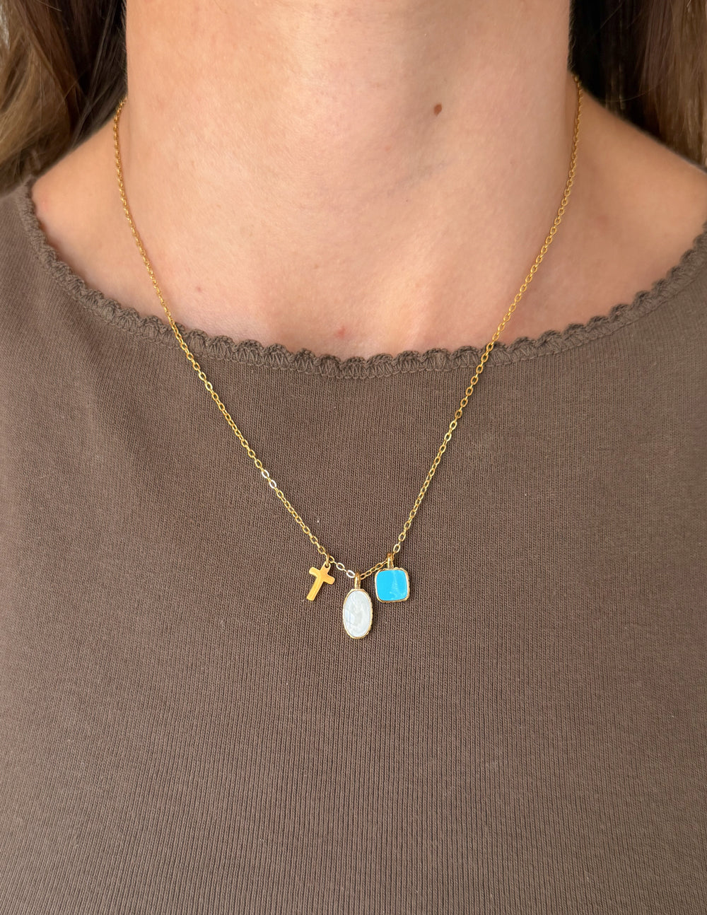 Gold charm link necklace with cross and oval pendant plus blue square charm