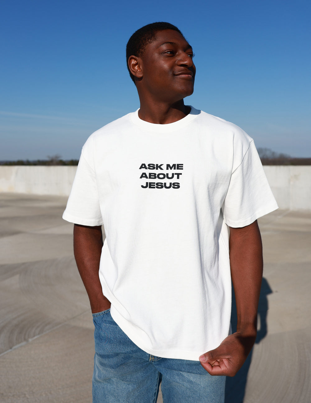 White heavyweight T-shirt with black chest text: Ask Me About Jesus.
