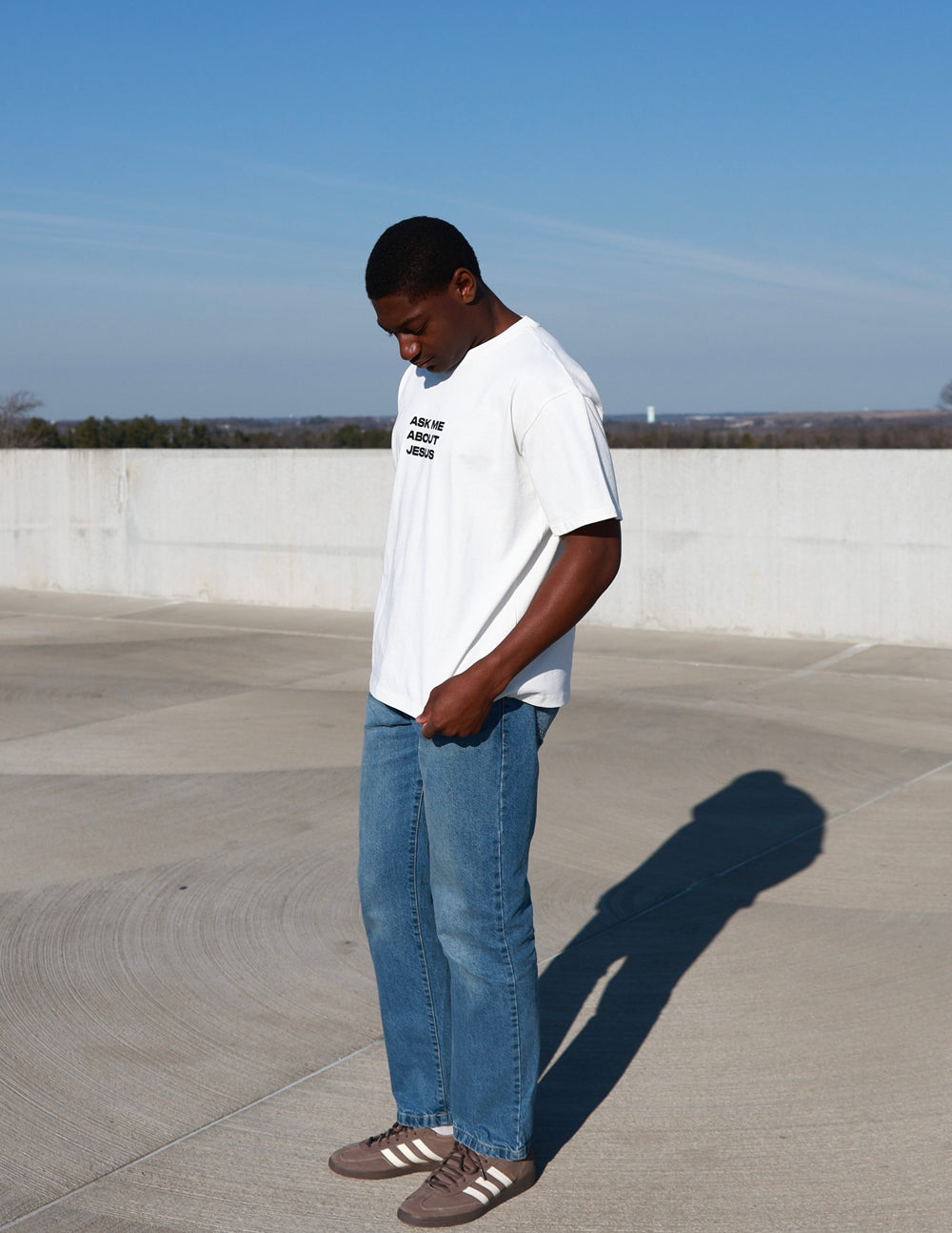 White heavyweight T-shirt, side view, black chest graphic text: Ask Me About Jesus.