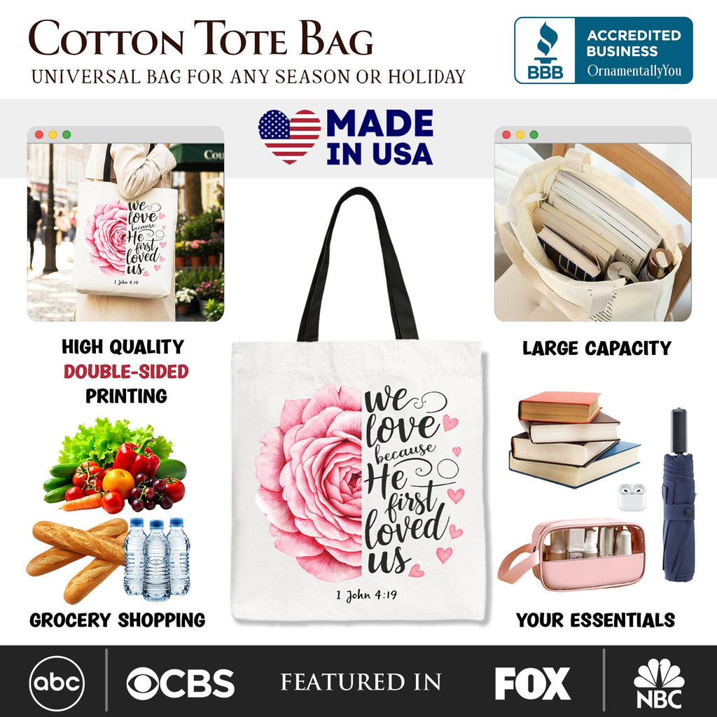 White tote bag with pink rose front print, '1 John 4:19' text, black handles
