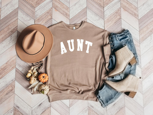 Tan crewneck sweatshirt with bold white "AUNT" graphic on the front