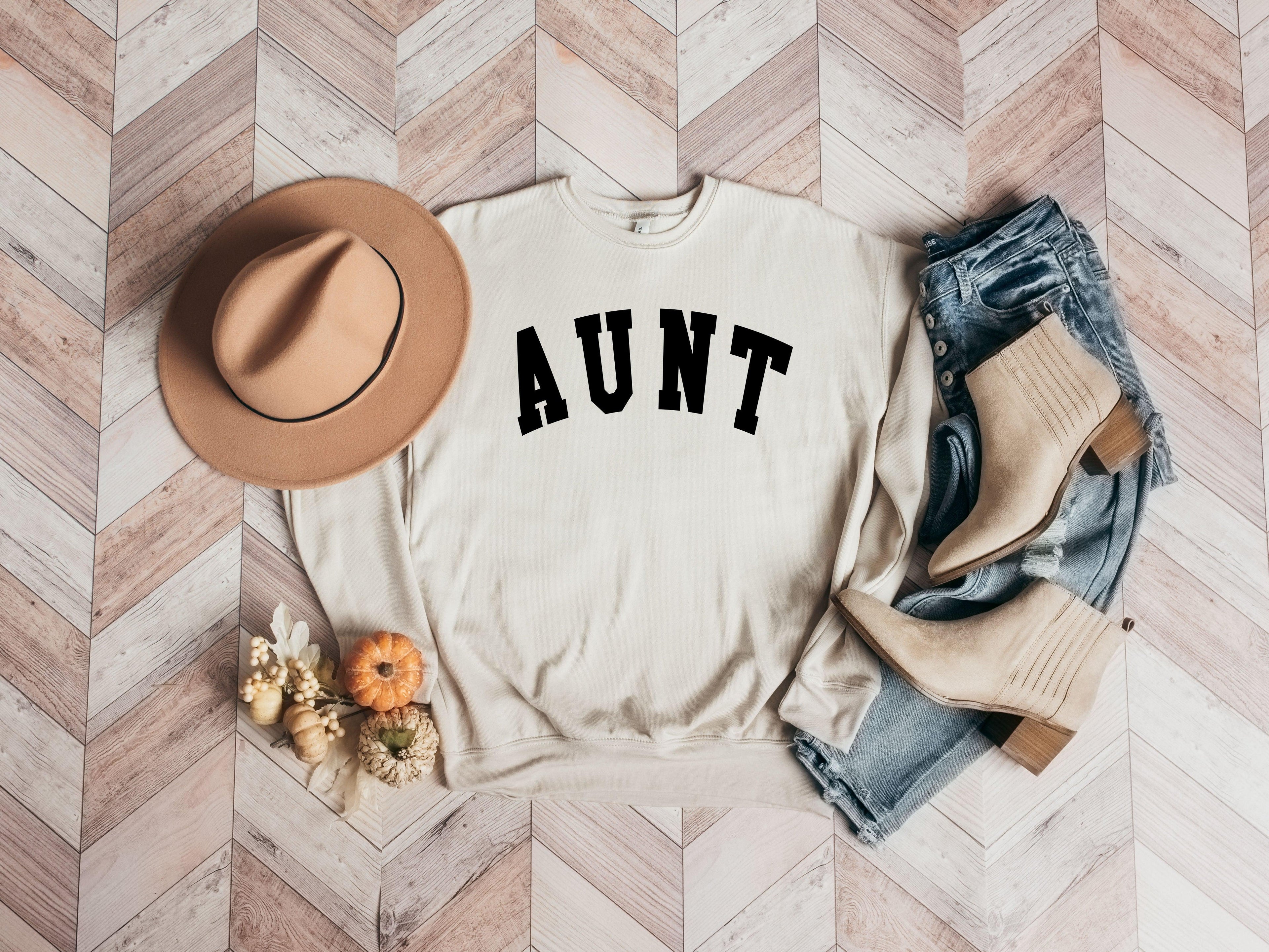 Cream crewneck sweatshirt with black "AUNT" graphic on the front