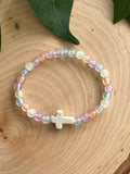 Colorful bead bracelet with a white cross charm and pastel purple, blue, and cream beads.