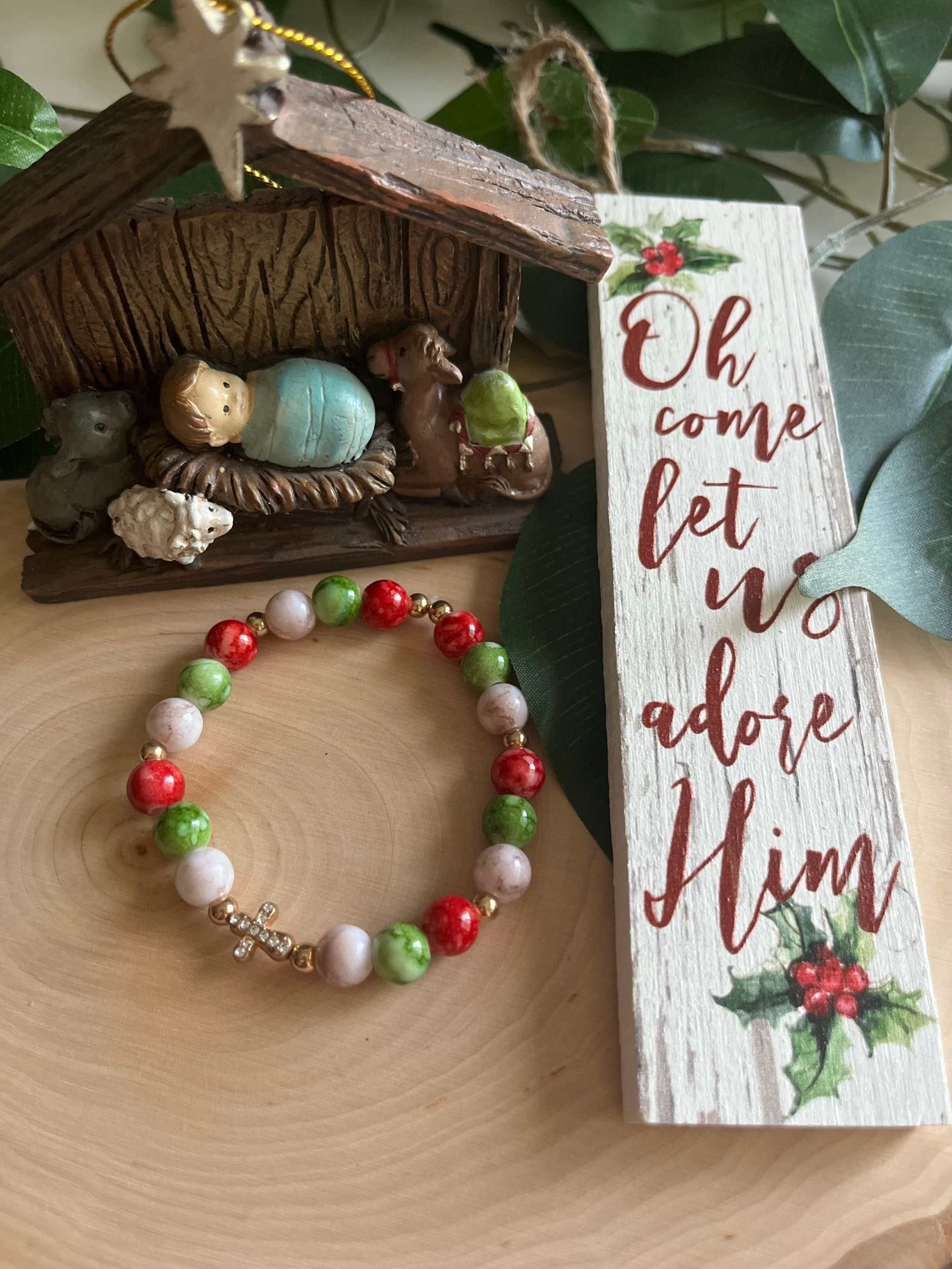 Beaded bracelet with red, green, and white beads and a small silver cross charm