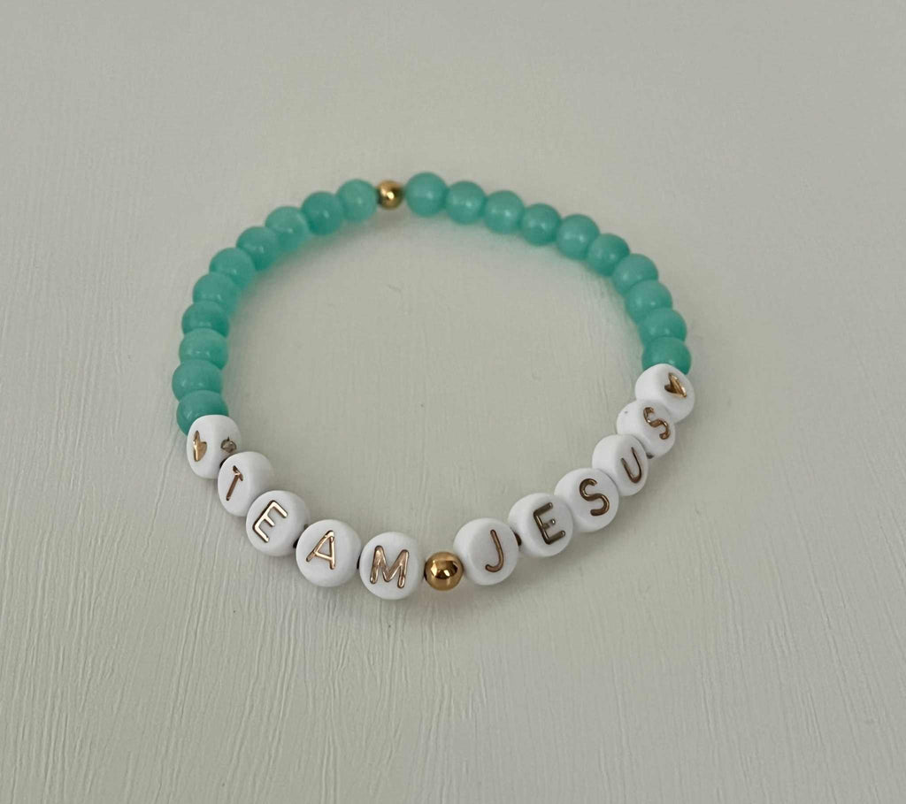 Opal-like iridescent beaded bracelet with teal beads and white letter charms spelling TEAM JESUS