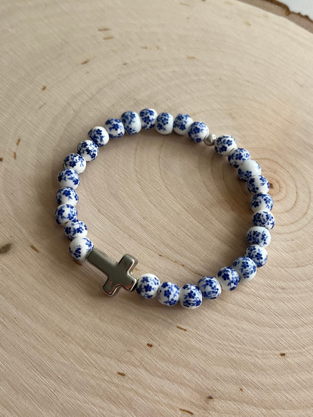 Blue speckled beaded bracelet with silver cross charm and elastic stretch band.