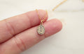 Bronze medal pendant on gold chain, small cameo shape in hand.