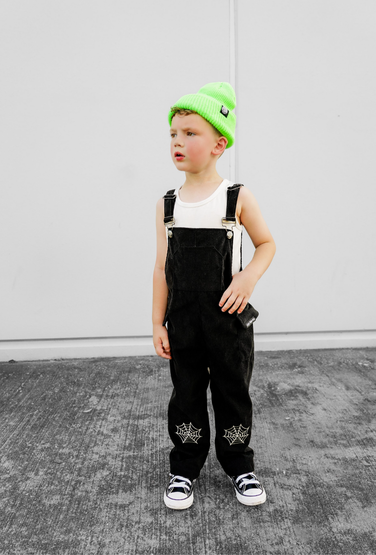 Black spiderweb overalls with adjustable straps, front pocket, and web prints on legs.