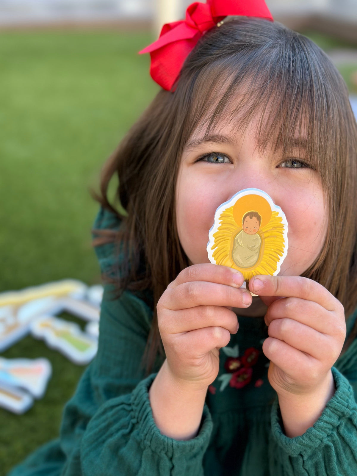Child holding a nativity figurine bath toy cutout near the face