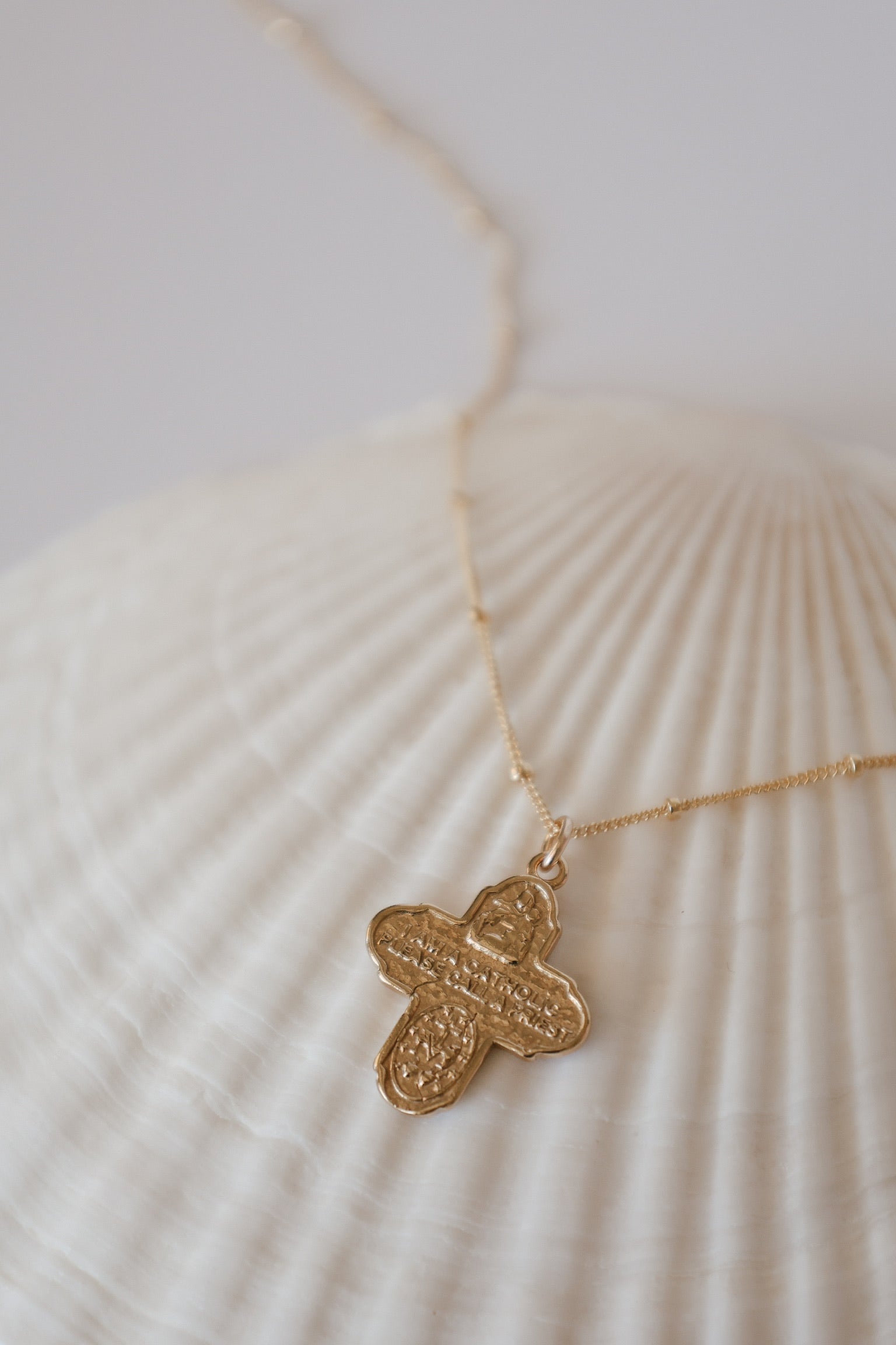 Gold cross necklace with textured filigree cross pendant on a thin chain