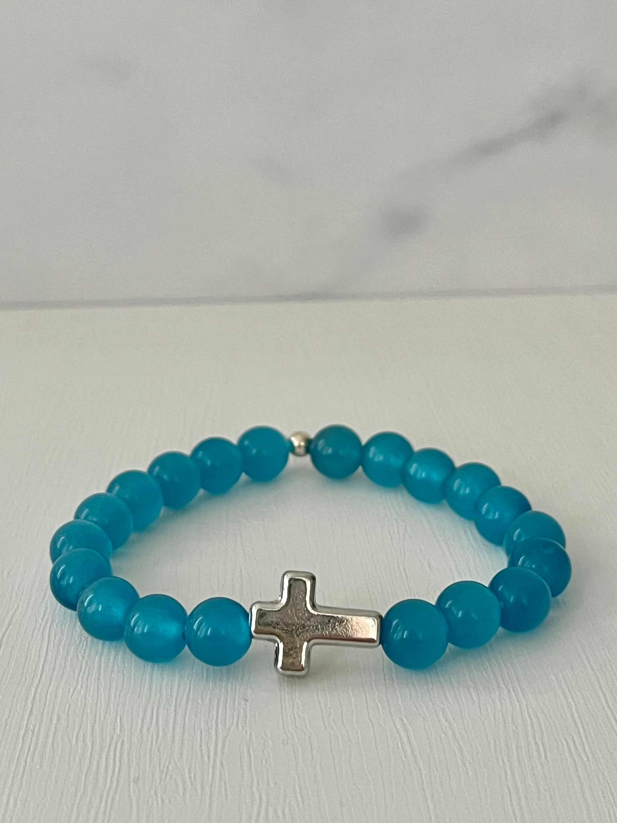 Turquoise beaded cross bracelet with silver cross charm on a loop.
