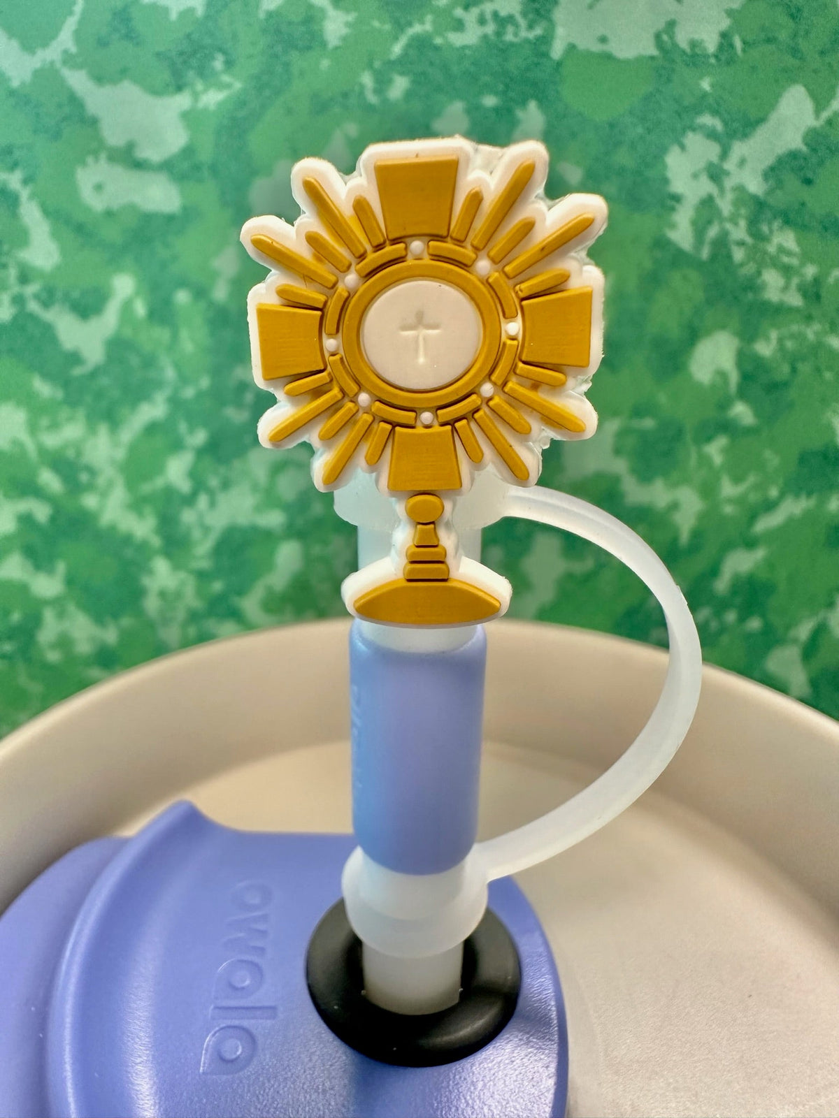 Close-up of gold Adoration straw topper with cross and chalice on blue straw
