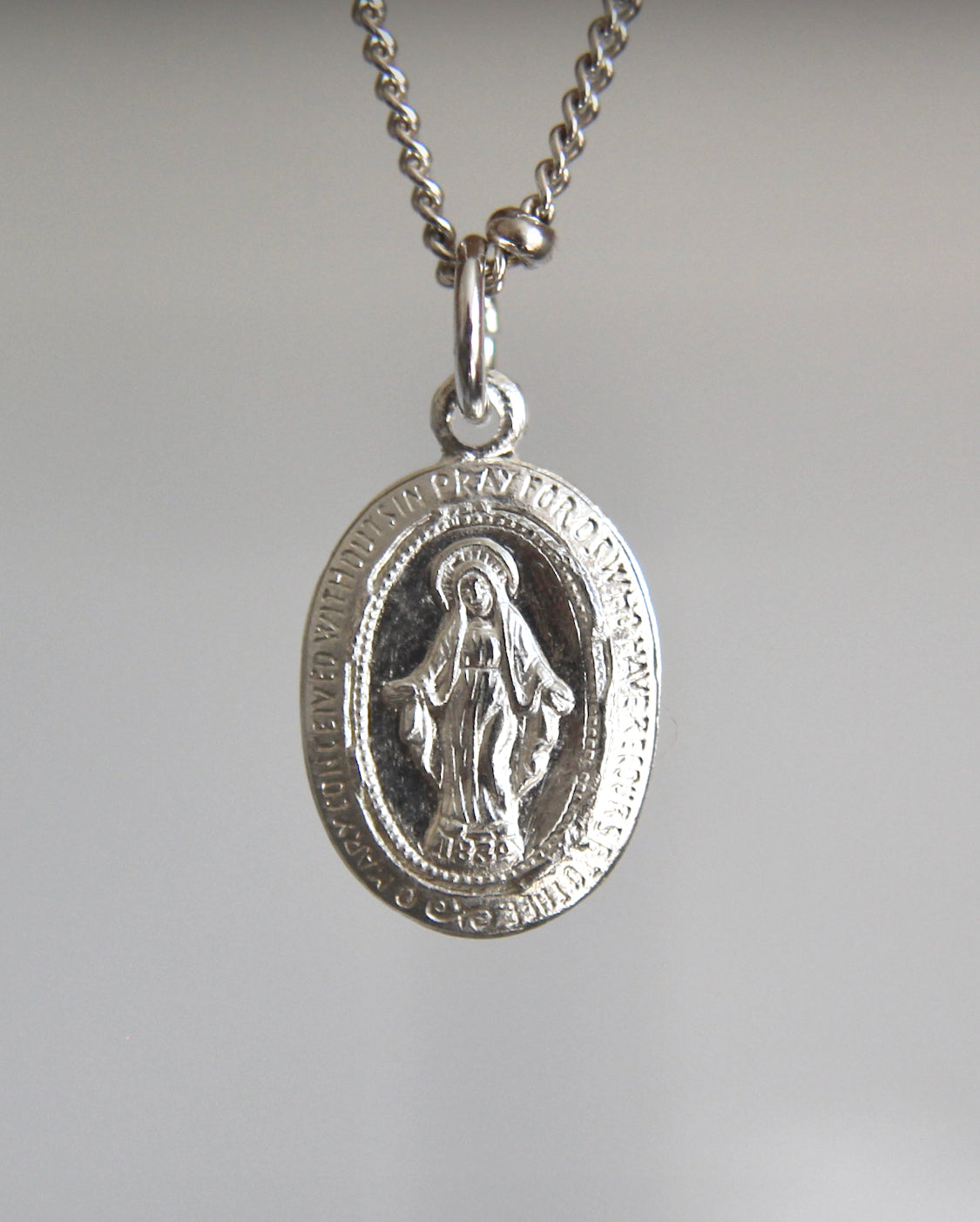 Silver miraculous medal pendant necklace with detailed oval coin-style medal