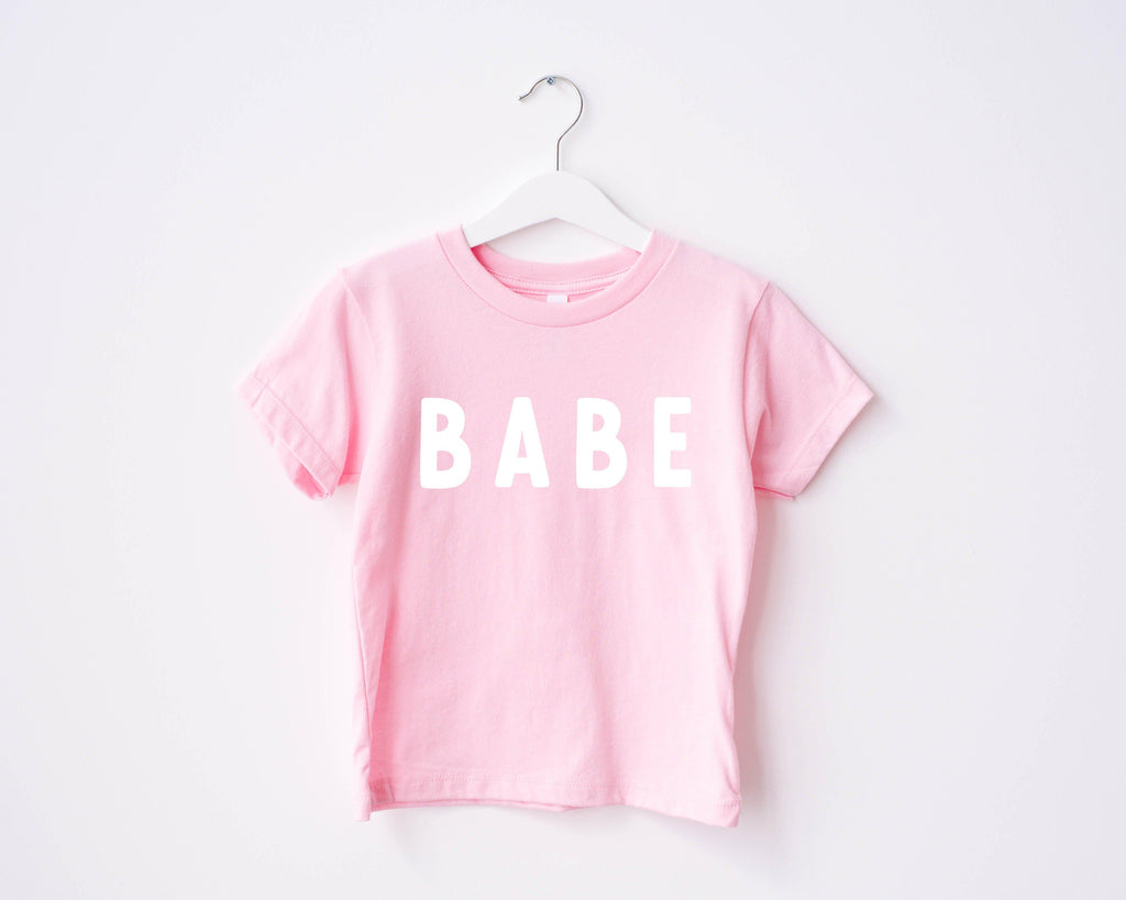 Pink baby T-shirt with white "BABE" rounded-letter print
