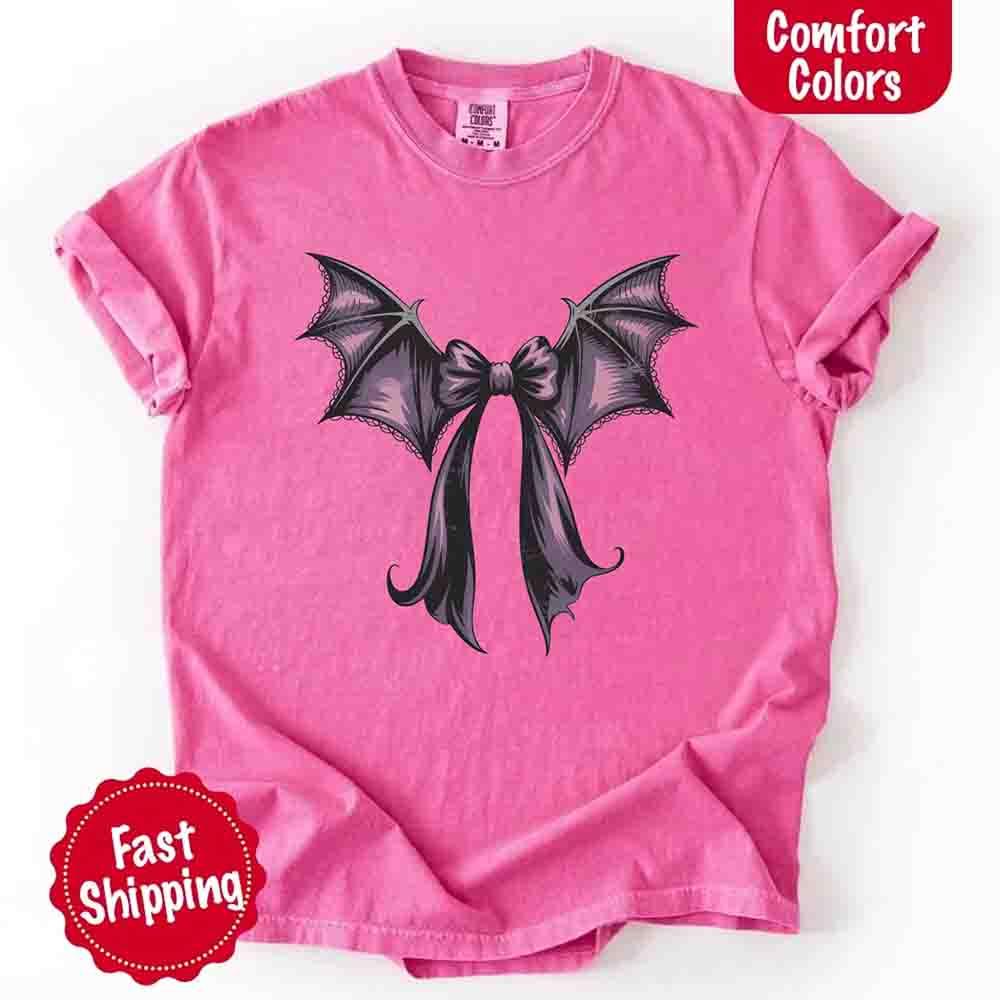 Light pink Halloween T-shirt with black and purple bat bow graphic at center