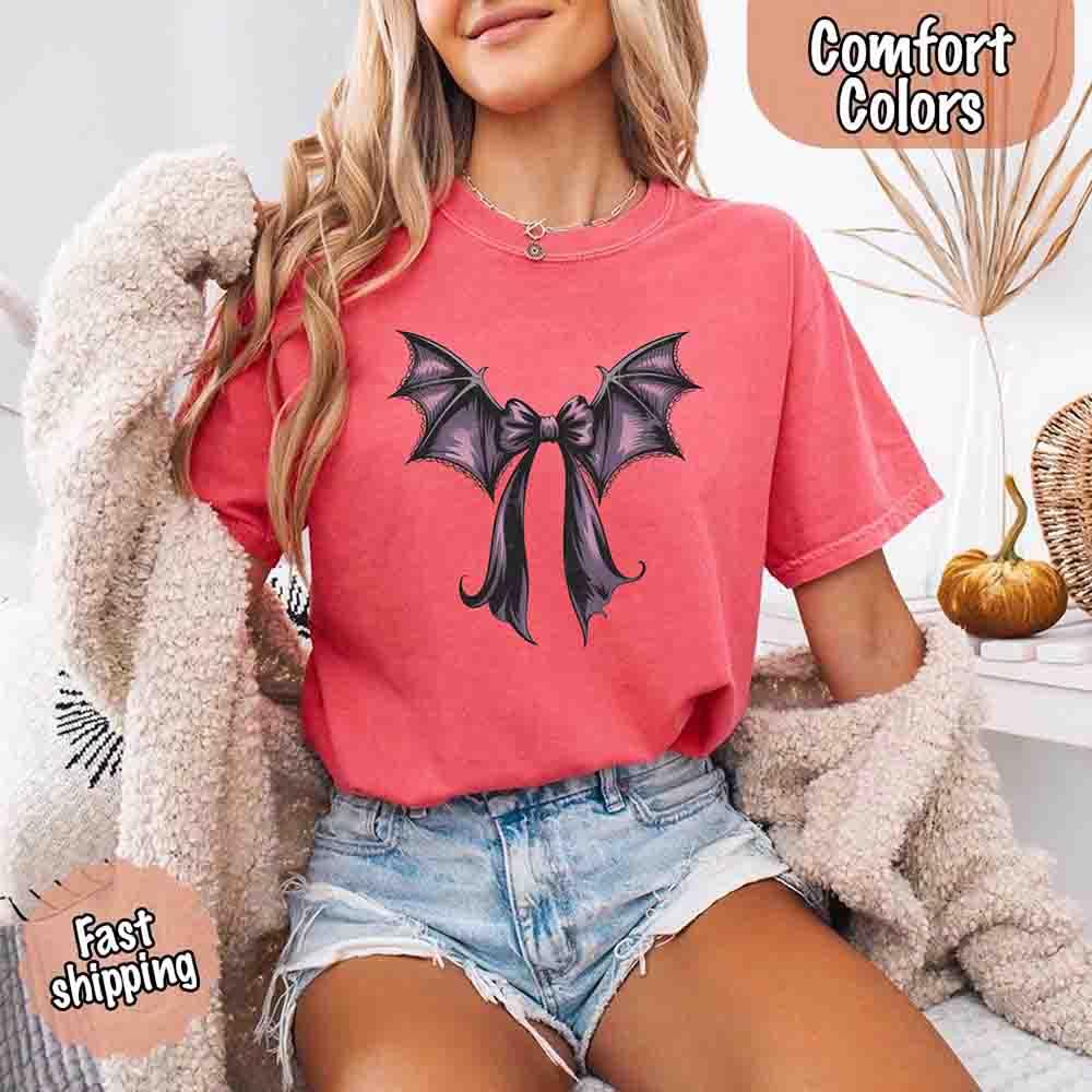 Coral pink Halloween T-shirt with black and purple bat bow graphic on front
