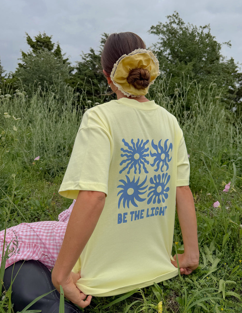 Yellow unisex T-shirt back with large blue sunburst graphic and BE THE LIGHT text