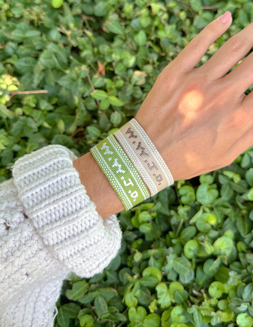 Beige woven bracelet with green-and-white embroidered WWJD on wrist