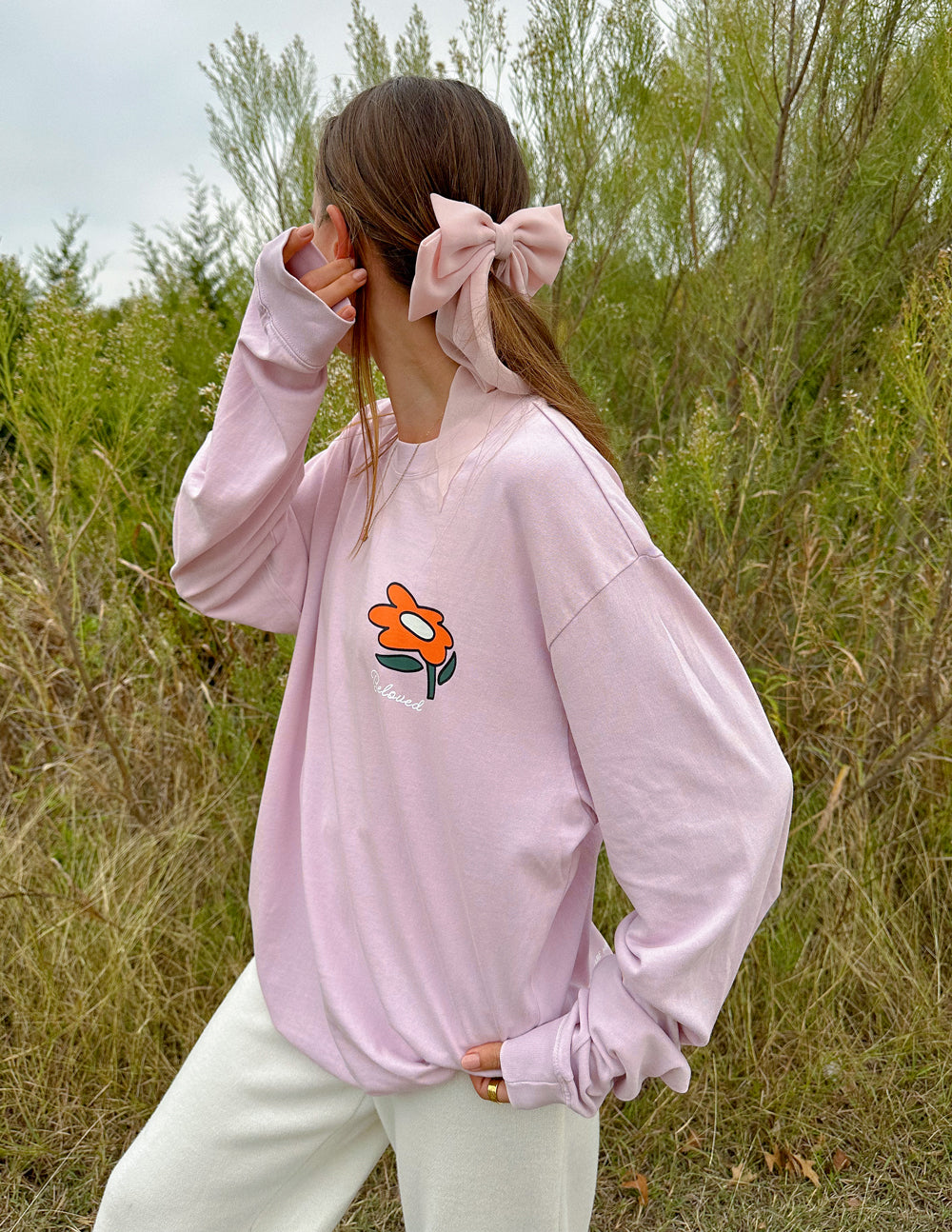 Light purple long-sleeve unisex tee with small orange flower logo on chest