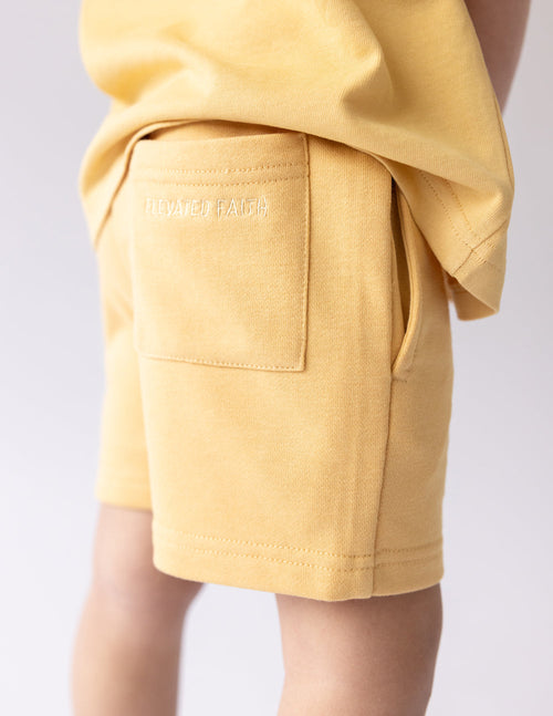 Kids yellow shorts with side pocket panel and subtle butterfly logo