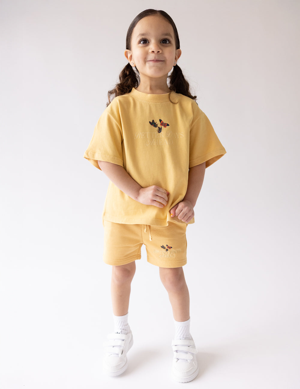 Kids yellow butterfly graphic shorts worn with matching top and socks