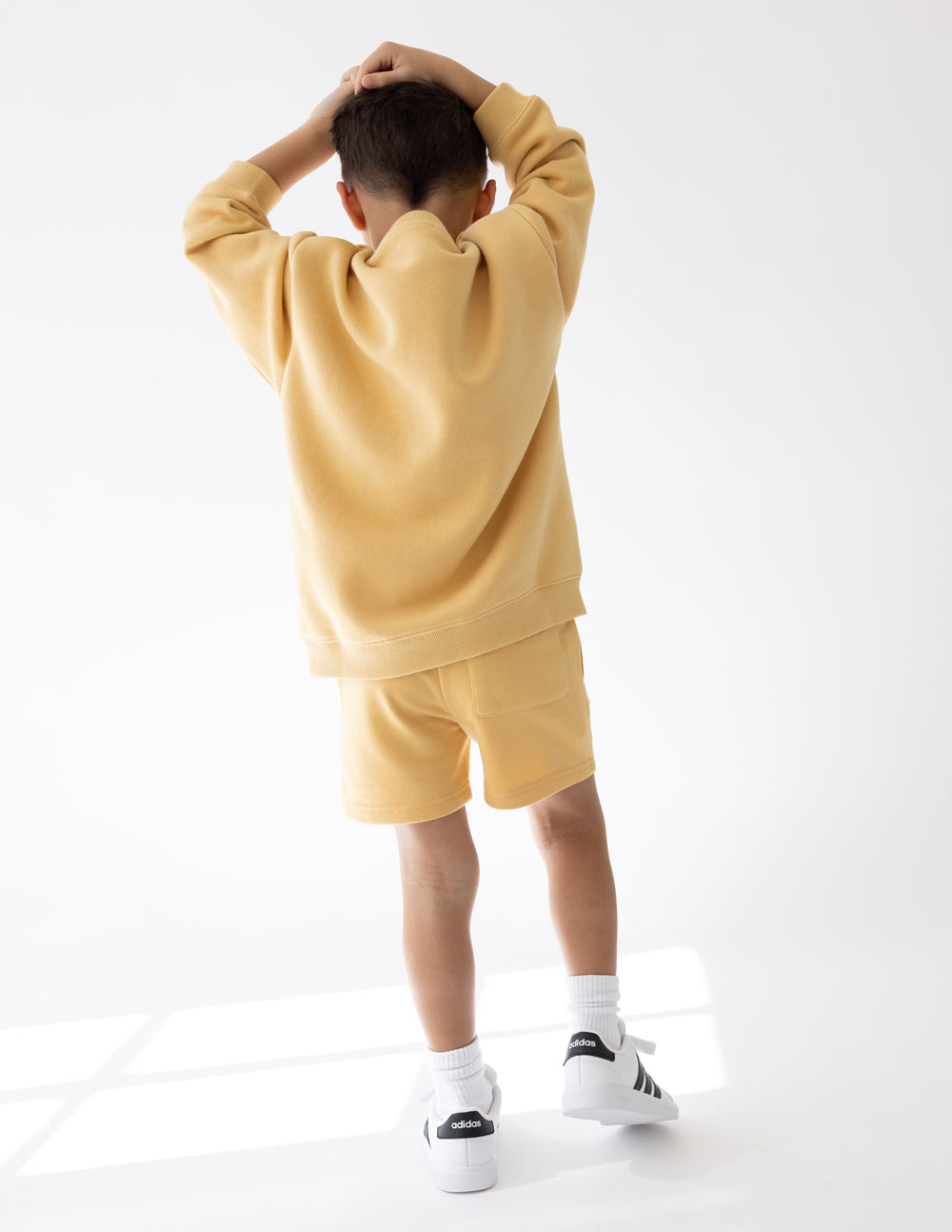 Kids yellow shorts with adjustable drawstring waistband worn from behind