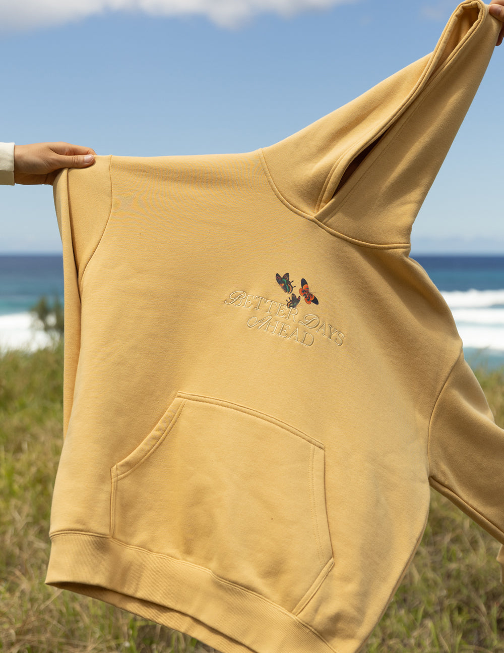 Tan pullover hoodie with kangaroo pocket and butterfly graphic on front