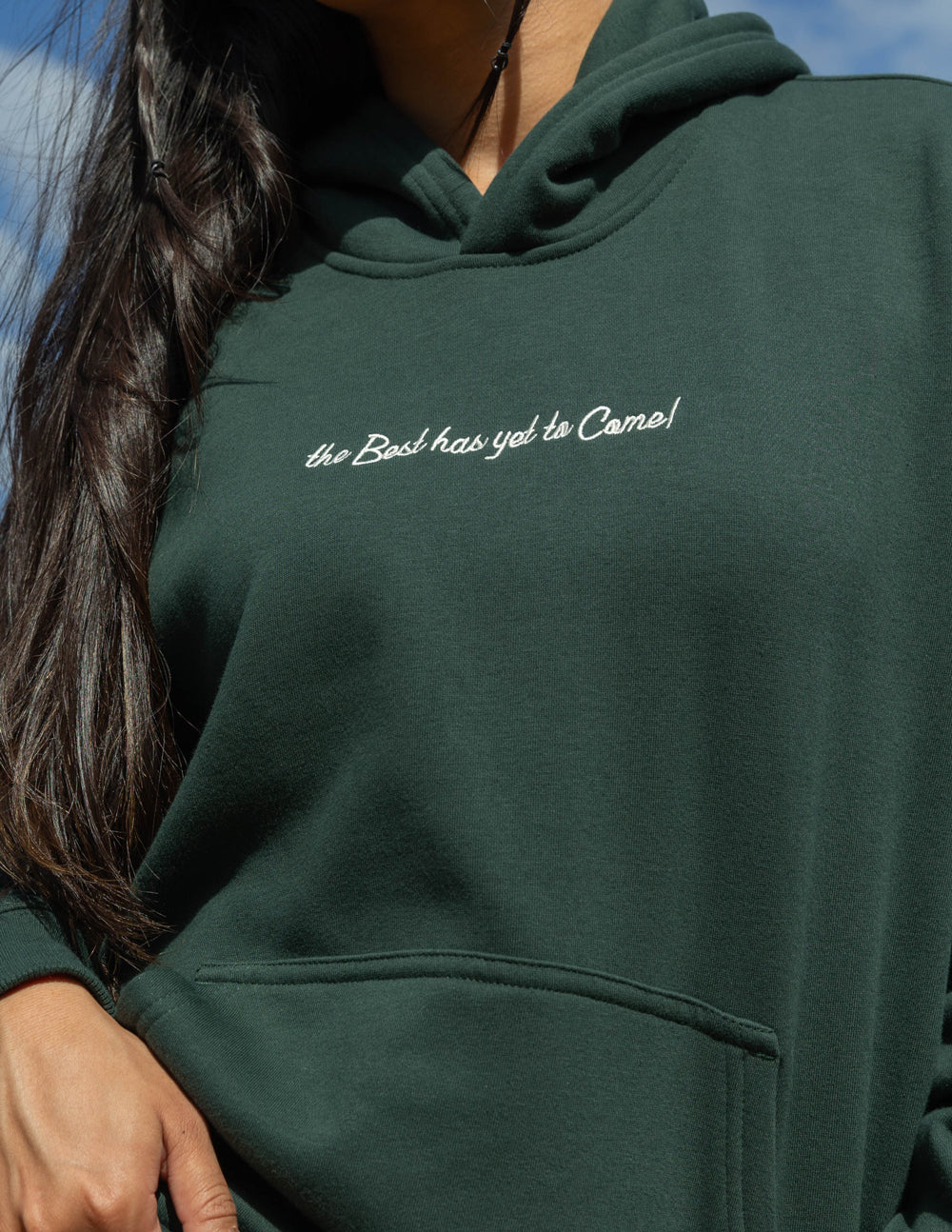 Dark green unisex hoodie close-up of hood and small chest script logo