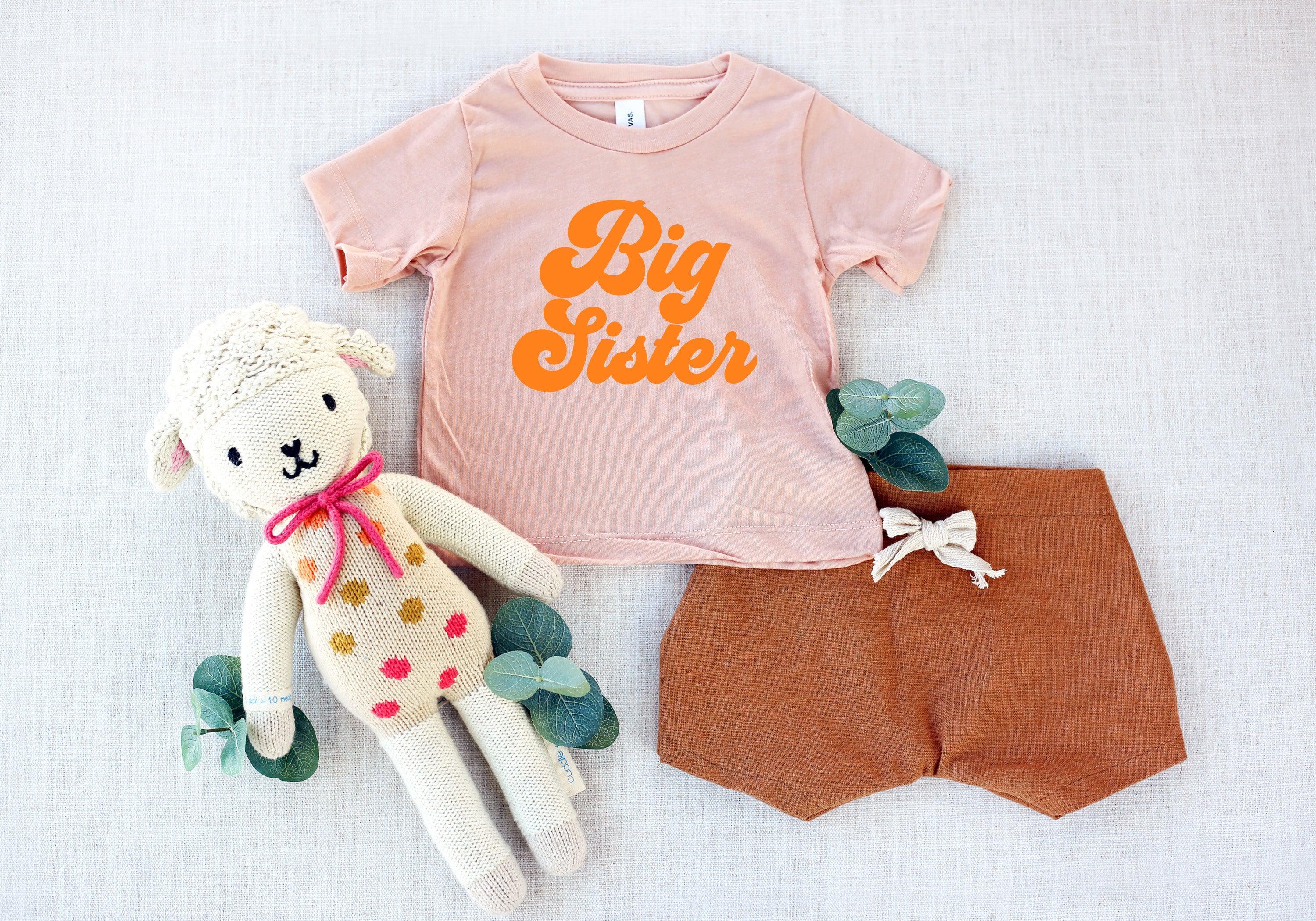 Light pink T-shirt with orange 'Big Sister' logo and matching shorts