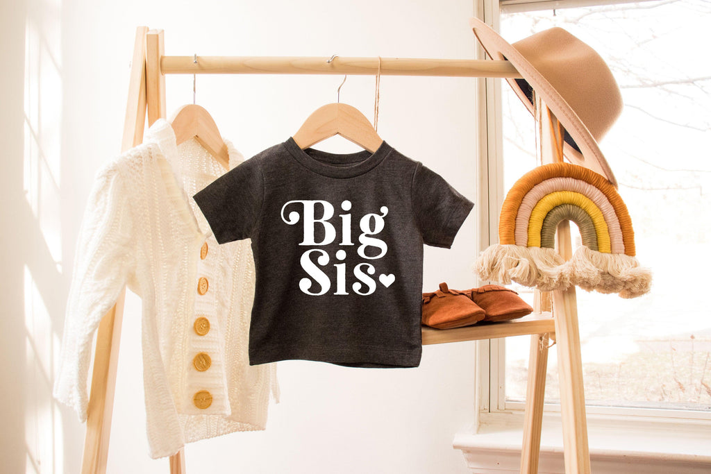Black baby T-shirt with Big Sis heart retro print on a hanger