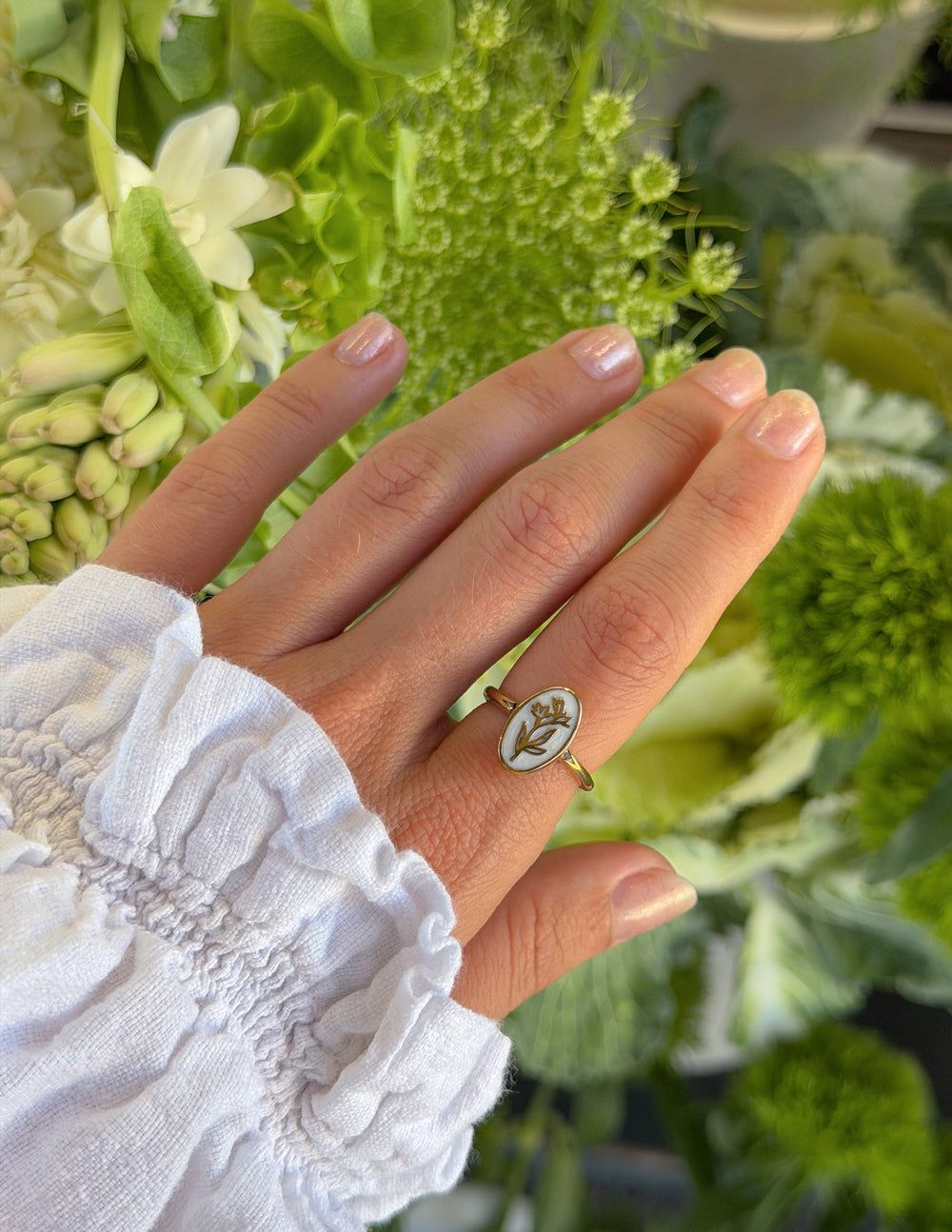 Gold enamel oval floral ring with detailed botanical design