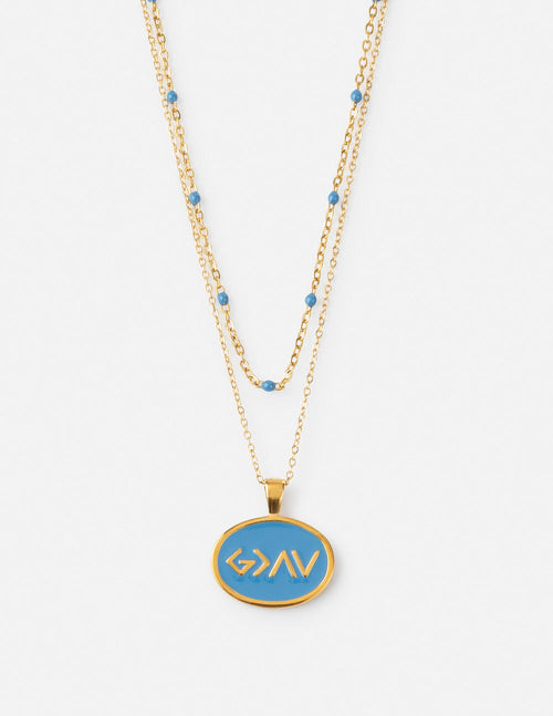 Layered gold necklace with blue bead accents and oval medallion pendant.