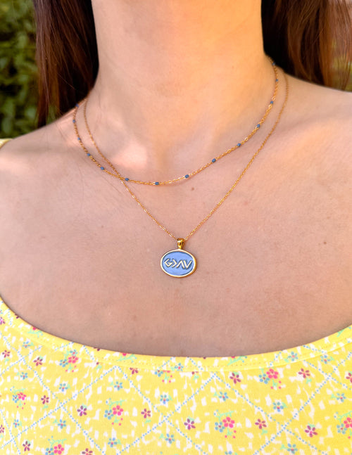 Gold and blue necklace set with oval pendant and beaded chain, layered look.