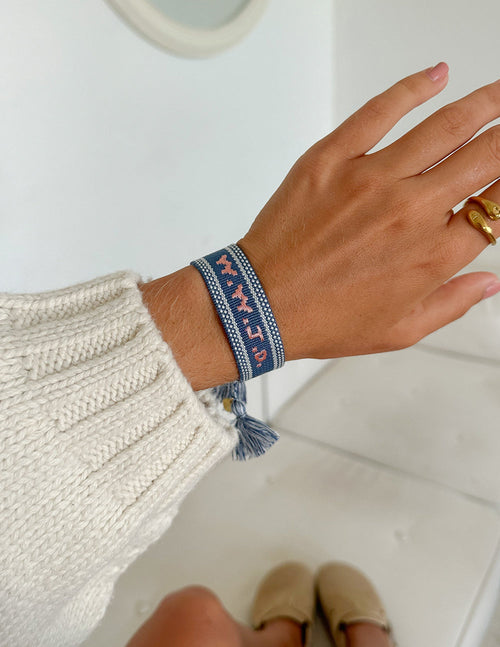 Blue embroidered bracelet on wrist with tassel detail on band end