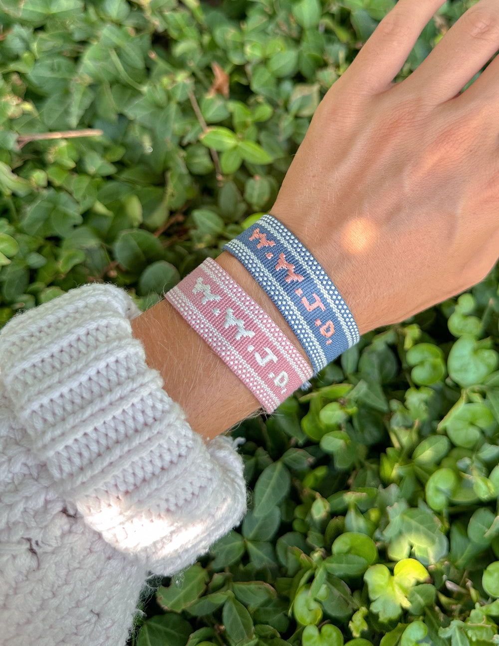 Blue woven bracelet with embroidered pattern, pink accents, tasseled end