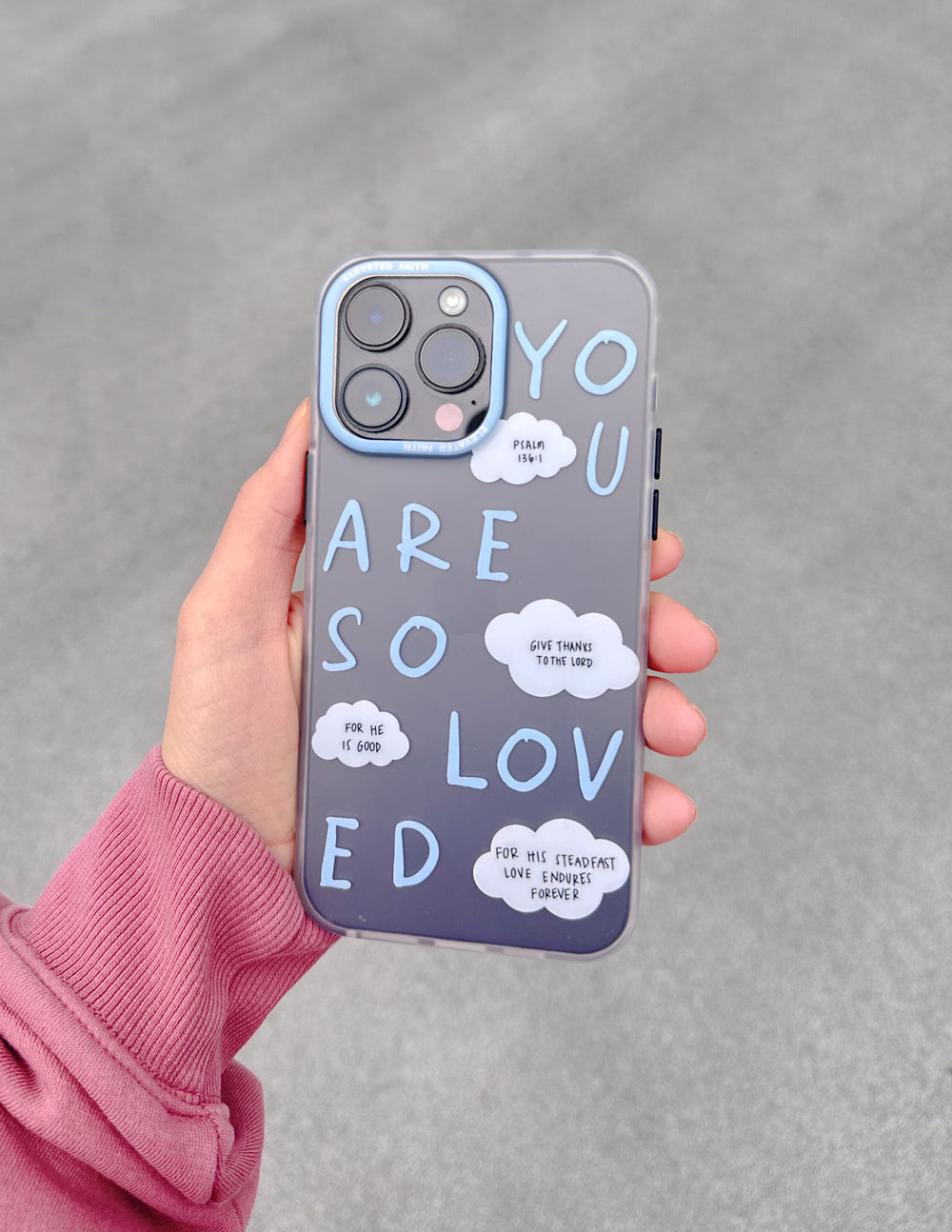 Frosted blue phone case held in hand showing white word art and camera cutouts