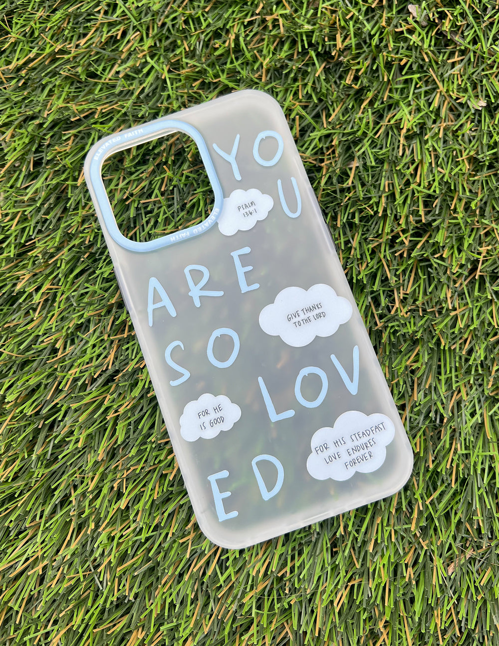 Frosted blue phone case with white word art, cloud stickers, and camera cutouts