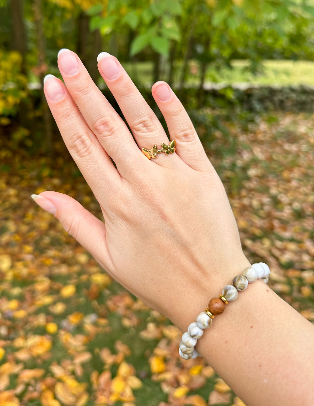 Gold butterfly motif ring with green stone accents on hand