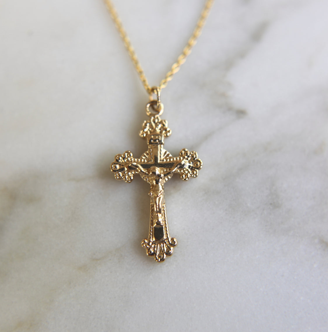 14k gold crucifix pendant on a chain, centered front view with ornate edges.