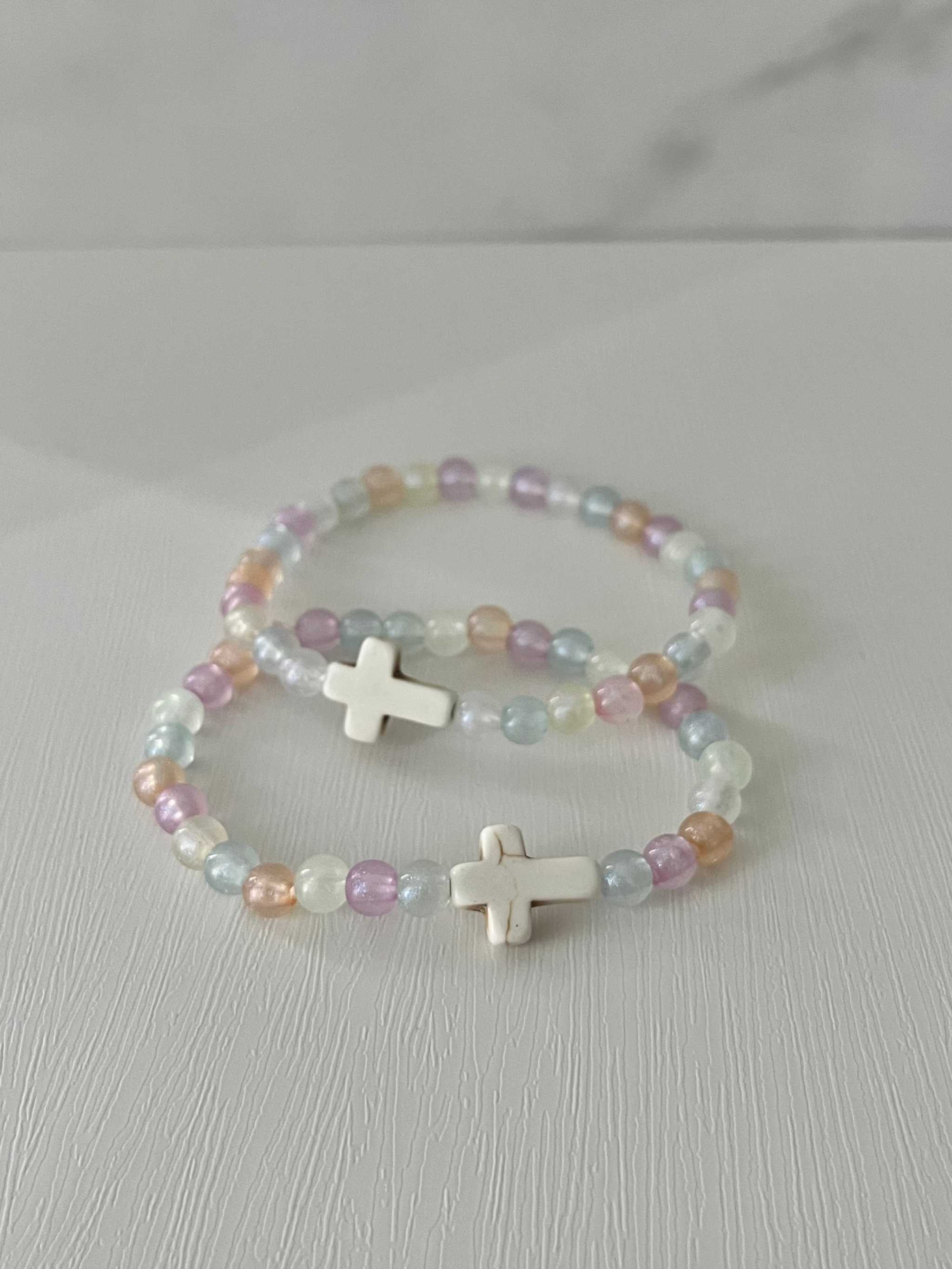 Two pastel beaded bracelets with white cross charms and multicolor beads.