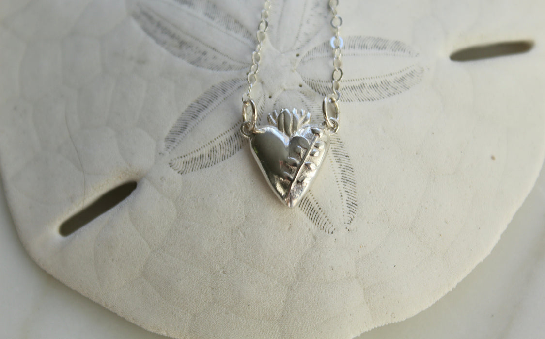 Sterling silver heart pendant necklace on a white lace disc, raised heart and chain